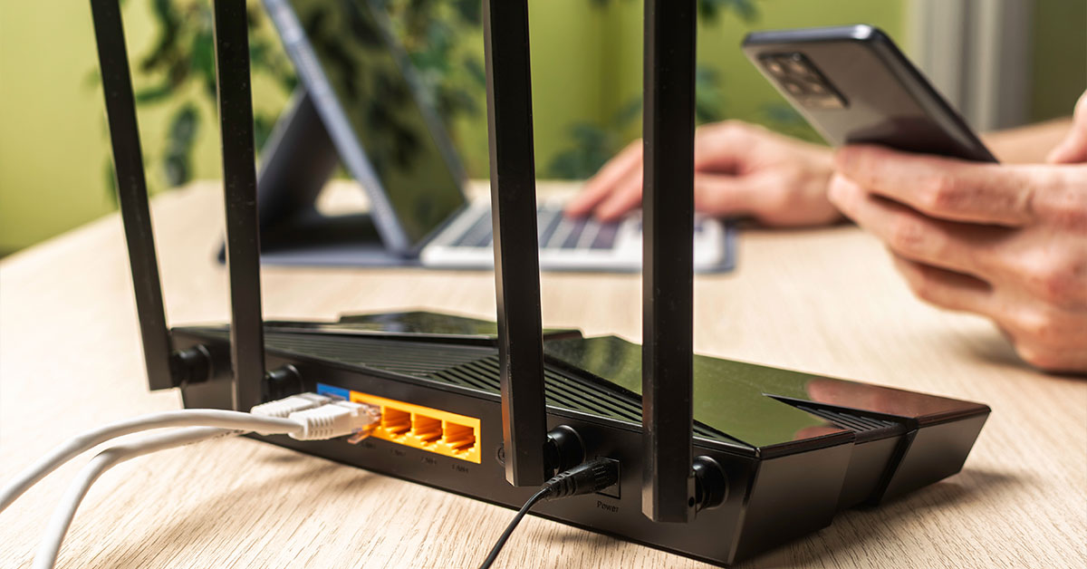Tech support working on laptop and phone in front of black router